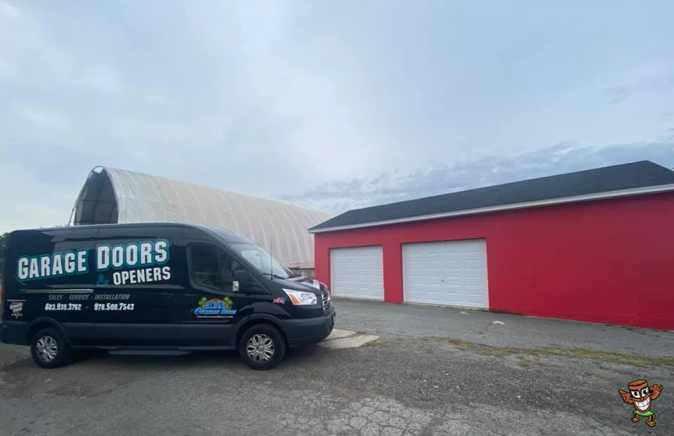 A company service van parked outside a bright red commercial facility with white overhead bay doors, representing a Commercial Overhead Door Company.